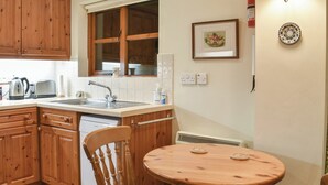 Une cuisine avec des meubles de rangement en bois, un évier, une cuisinière et une table à manger avec des chaises.