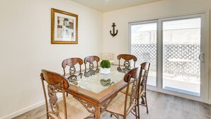 A dining area with a glass-top table, six wooden chairs, a small potted plant, a framed picture, and a wall-mounted anchor. - Kingman Vacation Rental w/ Yard + Fire Pit (Kingman)