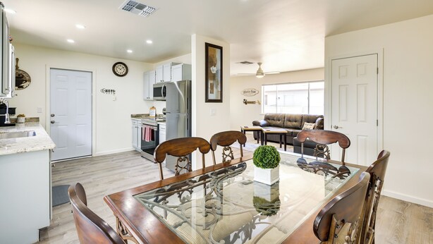 A dining area with a glass-top table, wooden chairs, and a potted plant. - Kingman Vacation Rental w/ Yard + Fire Pit (Kingman)