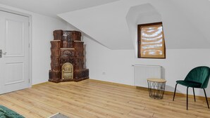 A room with a wooden cabinet, a radiator, a green chair, and a white door. - Hytta Apartment with 2 Bedrooms (Sinaia)