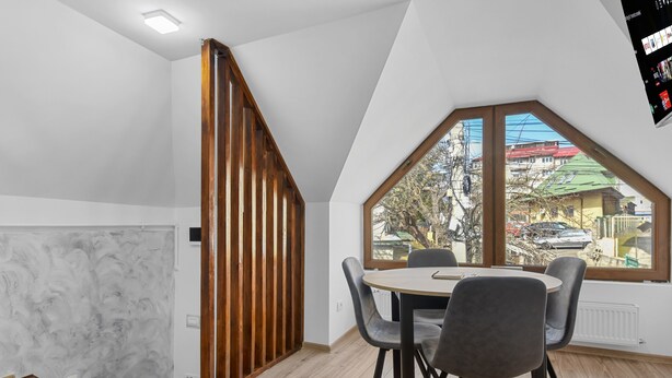 A modern room with a dining area, a wooden partition, and a large window with a view of the outside. - Hytta Apartment with 2 Bedrooms (Sinaia)