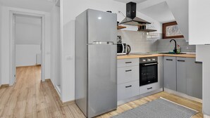 A modern kitchen with grey cabinets, a stainless steel refrigerator, a built-in oven, and a window above the sink. - Hytta Apartment with 2 Bedrooms (Sinaia)