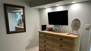 A bedroom with a bed, a dresser, a television, and a mirror. - Stunning Views from this lovely 2 bed/2bath (Galveston)
