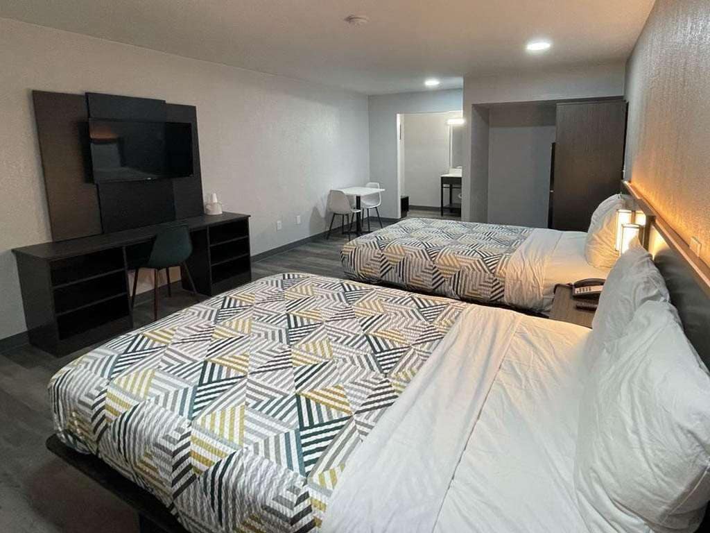 A hotel room with two beds, a TV, a desk, and a chair.