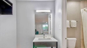 A bathroom with a white sink, mirror, and toilet. There is a towel rack with towels hanging on it. - Studio 6 Texarkana, Tx (Texarkana)