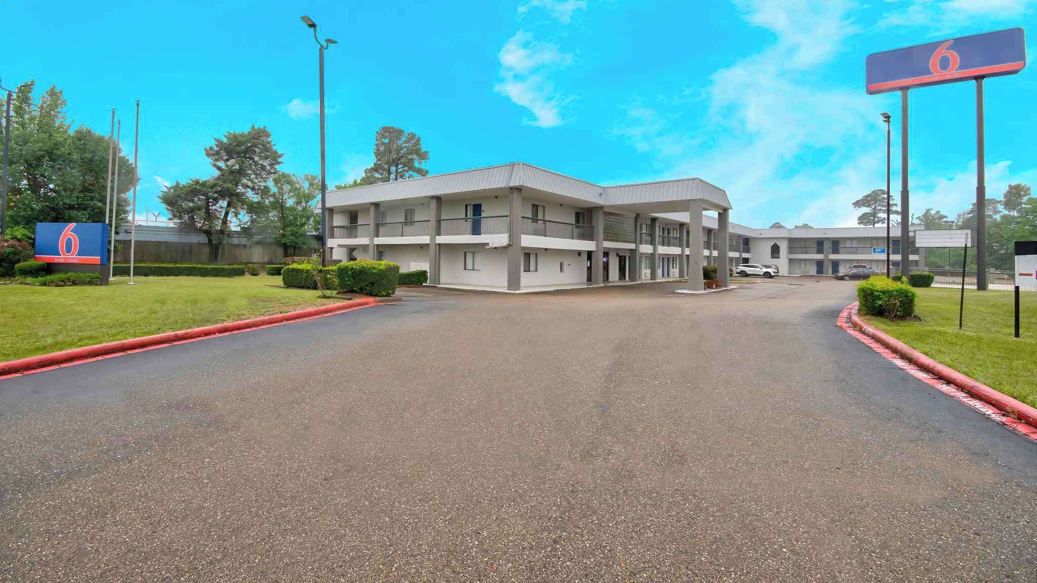 A multi-story hotel with a flat roof and a parking lot.
