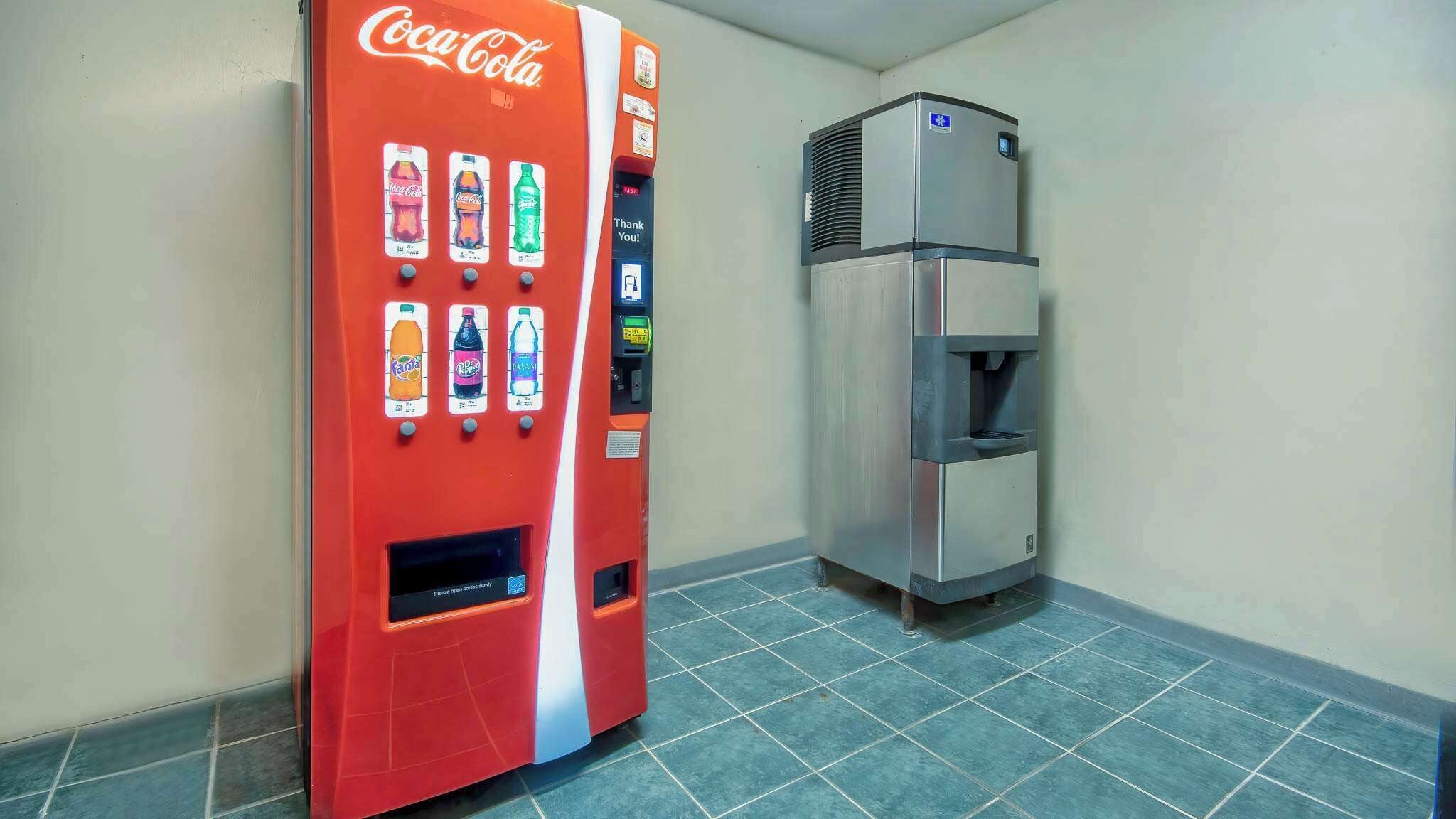 Una máquina expendedora con diversas opciones de bebidas, incluyendo Coca-Cola, Fanta y Sprite, y un dispensador de agua.