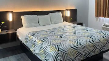 A modern hotel room with a large bed, two bedside tables, and a headboard with integrated lighting.