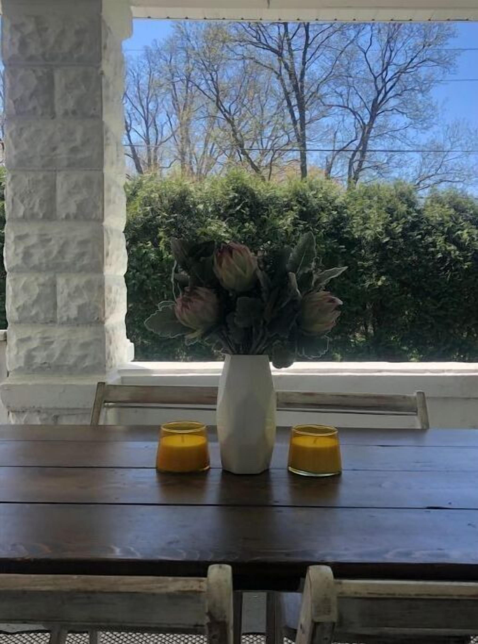 Mesa de jantar com um vaso branco e duas velas.