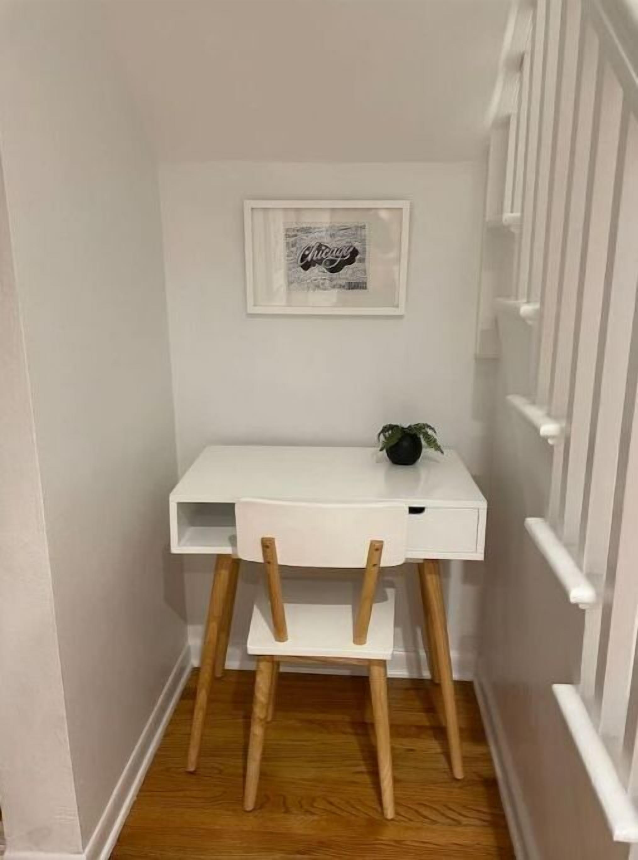 Un pequeño escritorio blanco con una silla en un pasillo estrecho.