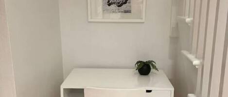 Un pequeño escritorio blanco con una silla en un pasillo estrecho.