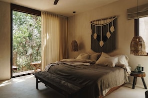 Relax in this serene bedroom with a large bed, a small table, and a window offering a view of lush greenery.