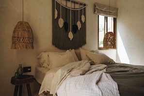 Et soveværelse med en seng, en hængende macramé-lampe og et vindue med udsigt.