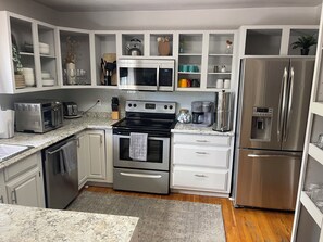 A modern kitchen with stainless steel appliances, white cabinetry, and a granite countertop.