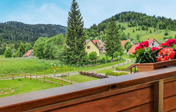 En vacker utsikt över ett lantligt landskap med hus, ett stort träd och en blomsterrabatt.