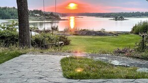 A stone pathway leading to a grassy area with a view of a lake and sunset. - Cozy home in Lidköping with WiFi (Lidköping)
