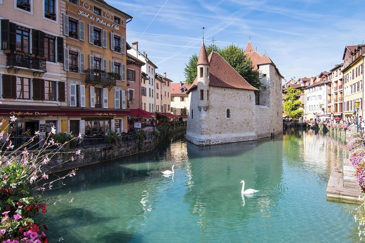 Ein Kanal mit Schwänen, umgeben von historischen Gebäuden und einem Steinpfeiler.