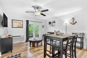 A dining area with a table, chairs, a ceiling fan, and a view through a glass door. - Dunedins Waterfront Beso Del Sol (Dunedin)