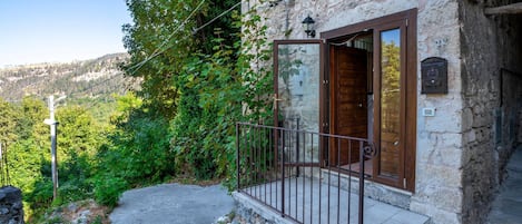 A stone building with a wooden door and a small balcony with a metal railing.