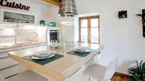 Et moderne køkken med en central ø, hvide skabe og et skilt med ordet 'Cuisine'.