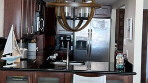 A modern kitchen with dark wood cabinets, stainless steel appliances, and a unique circular chandelier.