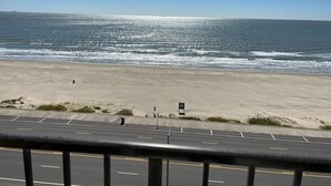 A beach with a road in the foreground and a clear sky.