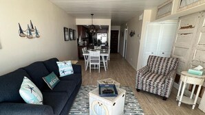 A living room with a sofa, a patterned armchair, a small table, and a rug.