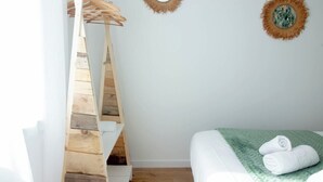 Quarto com escada de madeira, cama com manta verde e dois espelhos fixados na parede.