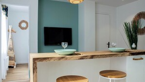 Cozinha moderna com uma parede de destaque azul-turquesa, balcão de madeira e dois banquinhos.