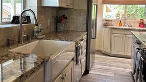 A kitchen with a granite countertop, stainless steel appliances, and light-colored cabinetry.