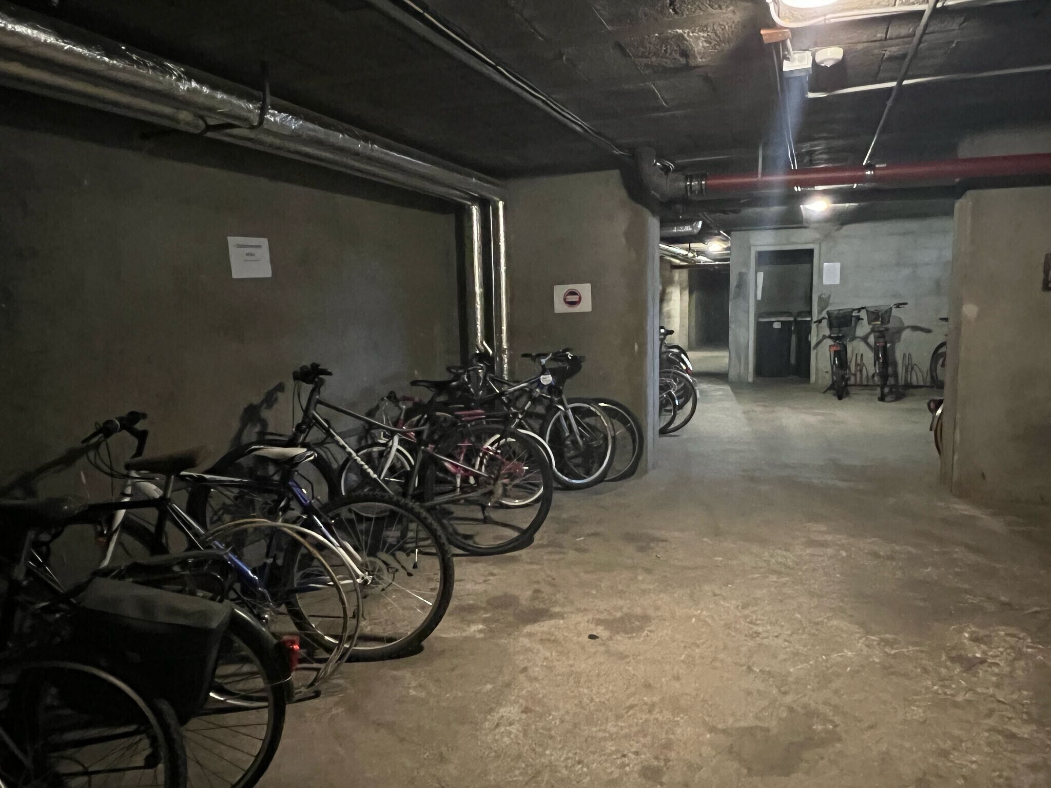 Garagem de estacionamento com bicicletas apoiadas nas paredes.