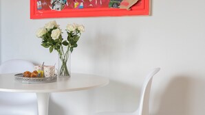 Una mesa blanca con un jarrón de rosas blancas y una bandeja de pasteles.