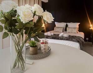 Ein Schlafzimmer mit einem Bett, Kissen und einem Nachttisch mit einer Vase weißer Blumen.