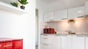 Una cocina moderna con armarios blancos, un microondas rojo y un electrodoméstico rojo con la etiqueta 'TELEFUNKEN'.