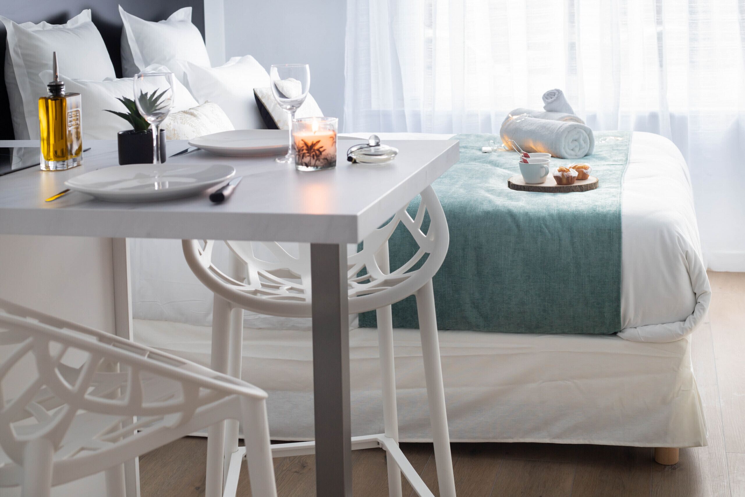 A neatly arranged bedroom with a bed, bedside table, and a dining area with a table set for two.