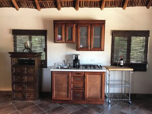A kitchen with wooden cabinets, a gas stove, a coffee maker, and a wine bottle on the counter.