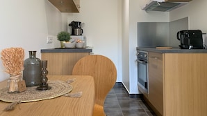 A compact kitchen with wooden cabinets, a coffee maker, and a microwave. - Secrets d ambre rue royale (Annecy)