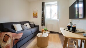 A modern living room with a sofa, coffee table, and a TV mounted on the wall. - Secrets d ambre rue royale (Annecy)