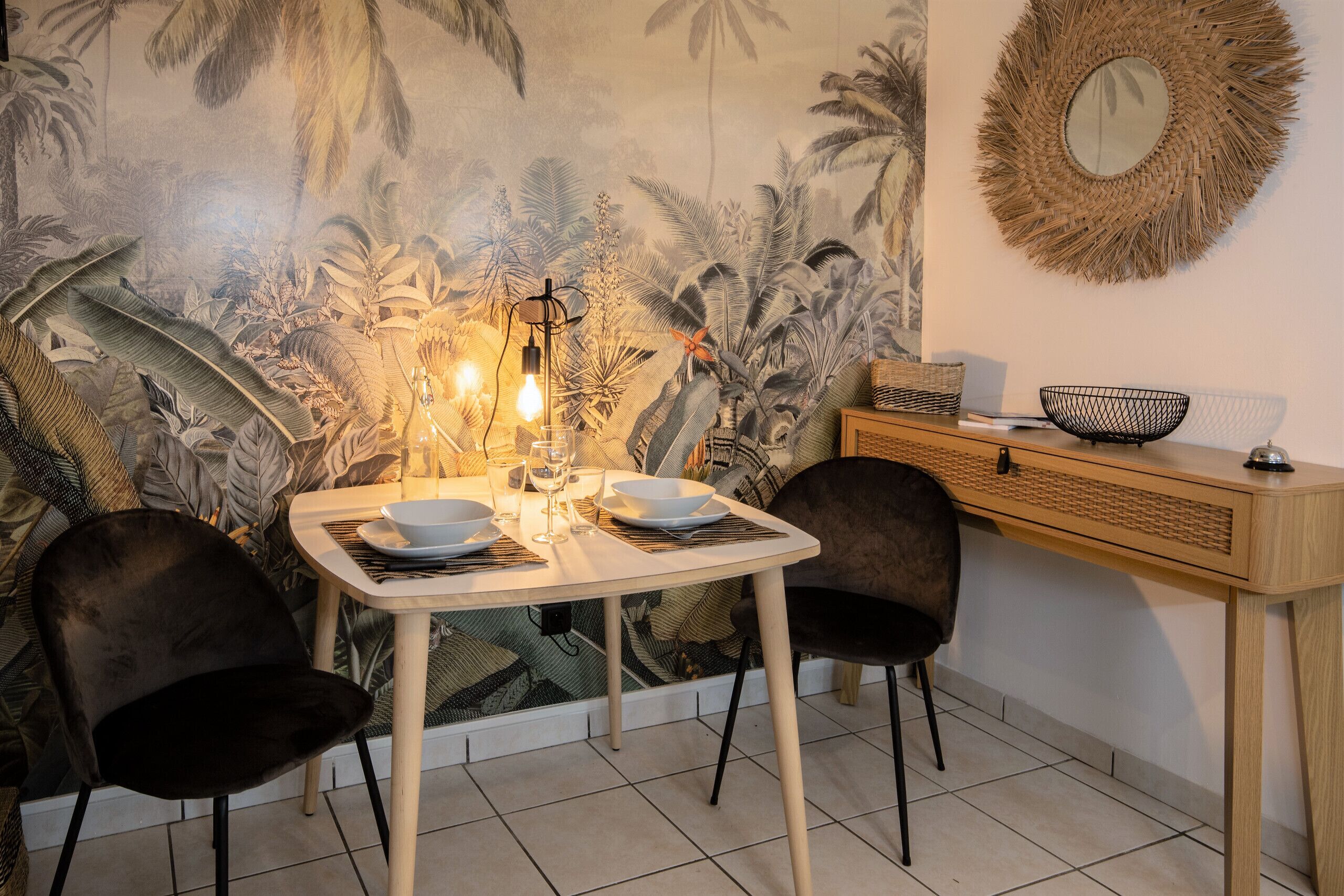 A dining area with a table set for two, a woven basket, and a wall-mounted mirror.