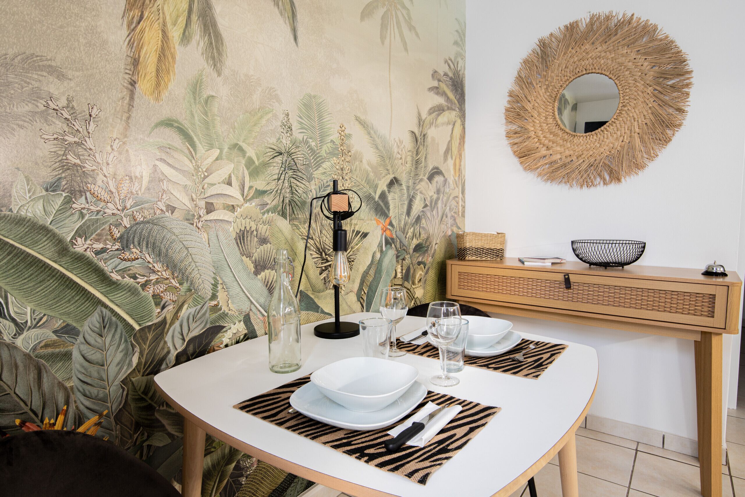 A dining table set with white plates, cutlery, and glasses, with a woven placemat and a woven placemat runner.
