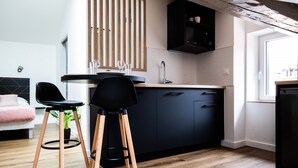 Een moderne keuken met donkere kastjes, een houten aanrecht en twee zwarte barkrukken.