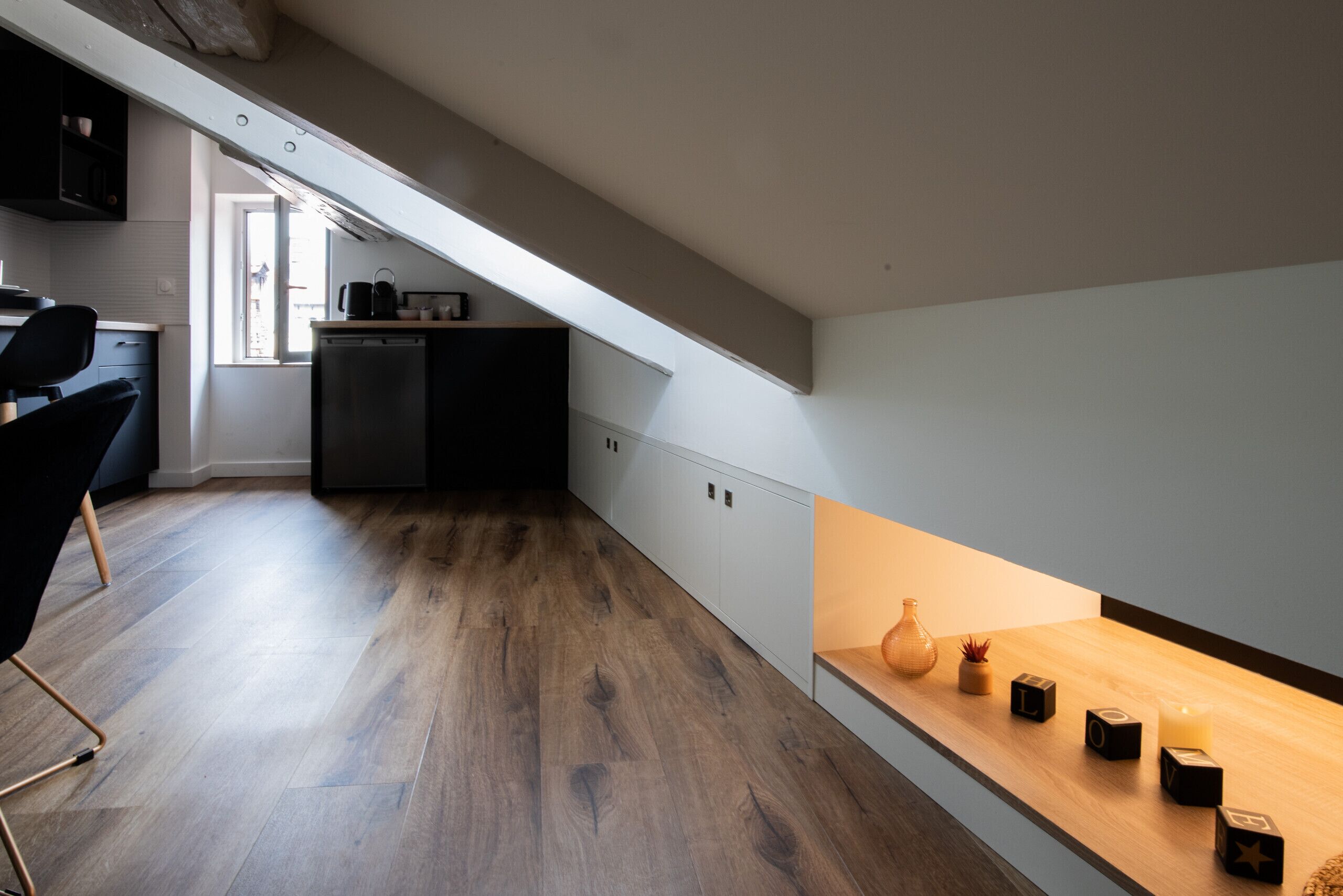 Een moderne keuken met een houten vloer, een inbouwoven en een raam.