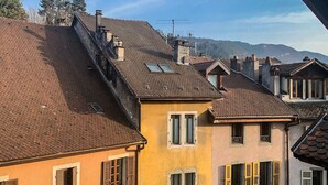 Een rij gebouwen met terracotta daken en traditionele luiken, gelegen tegen een heuvelachtige achtergrond.