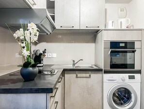 A modern kitchen with a built-in oven, microwave, and a washing machine. - Asana proche du lac, parking (Annecy)