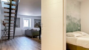 A room with a bed, a sofa, a ladder, and a door leading to another room. - Rainbow rue carnot 4 adultes et 1 enfant (Annecy)
