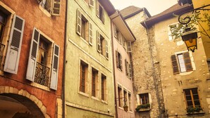 A narrow street with multi-story buildings featuring arched windows and shutters. - Rainbow rue carnot 4 adultes et 1 enfant (Annecy)