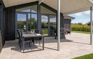 An outdoor patio with a table and chairs, a grill, and a glass enclosure. - 4 bedroom gorgeous home in Tarm (Tarm)