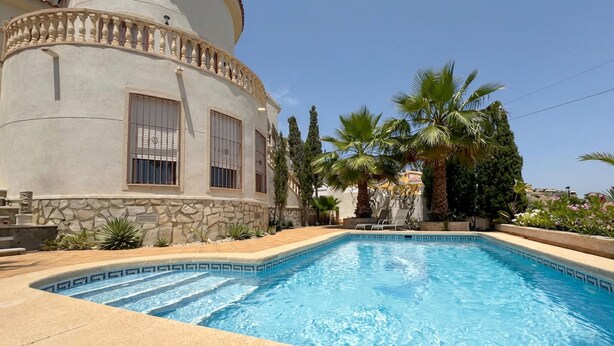 A swimming pool with a stone border, a stone wall, and a palm tree. - Beautiful home in Ciudad Quesada (Ciudad Quesada)