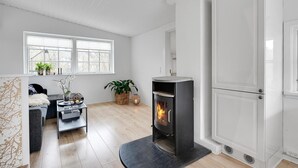En moderne stue med pejs, sofa, sofabord og spiseplads.