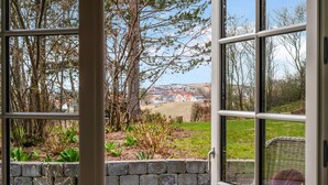 Udsigt fra et vindue med stenvægge og grønt, der kigger ud over et boligområde med huse og træer.